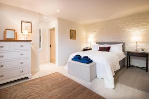 a bedroom with a large white bed and a dresser at The Bothy at Redheugh in Newcastleton