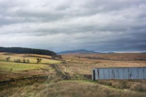 a field with a barn in the middle of a field at The Bothy at Redheugh in Newcastleton