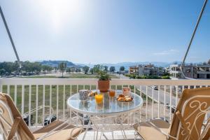 - une table sur un balcon avec deux verres de jus d'orange dans l'établissement Likno Apartment, à Nauplie