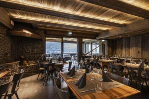 un restaurante con mesas y sillas de madera y ventanas en Hotel Bänklialp, en Engelberg