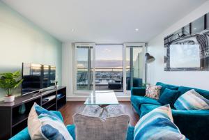 sala de estar con sofá azul y TV en Austin David Apartments ExCeL, en Londres