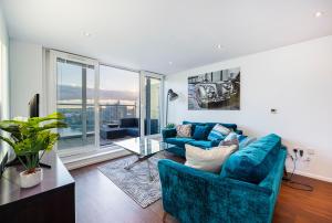 a living room with blue furniture and a large window at Austin David Apartments ExCeL in London