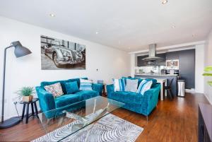 a living room with two blue couches and a kitchen at Austin David Apartments ExCeL in London