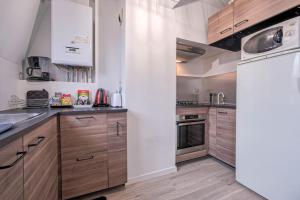 una cucina con armadi in legno e frigorifero bianco di Magnifique Duplex 2 à 6 personnes, parking gratuit, proche aéroport CDG a Villepinte