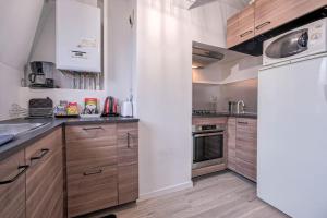 a kitchen with wooden cabinets and a white refrigerator at Villepinte, 2-4 pers, proche aéroport Roissy CDG, parc des expositions, Disney in Villepinte