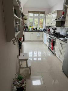 a kitchen with white cabinets and a table in it at Cosy and lovely 4-Bed House in Stanmore in Stanmore