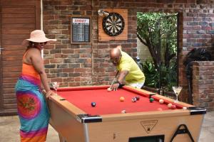 a man and a woman playing a game of pool at Arvella Guesthouse in Bloemfontein