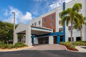 a hotel with a palm tree in front of a building at Hampton Inn West Palm Beach Central Airport in West Palm Beach