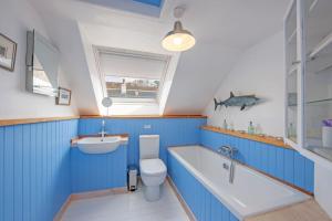 La salle de bains bleue est pourvue de toilettes, d'un lavabo et d'une baignoire. dans l'établissement Calgary Byre, à Calgary 6 autres photos
