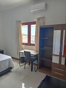 a bedroom with a desk and a bed and a window at D'eluxe Hotel Talara- ubicado a 5 minutos del aeropuerto y a 8 minutos del centro civico in Talara