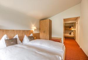 エンゲルベルクにあるHotel Bänklialpのベッドルーム1室(白いベッド2台付)、廊下が備わります。