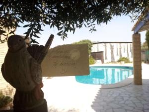 una statua di un uccello che tiene un cartello accanto alla piscina di Casa Rural La Noria a La Escucha