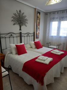 een slaapkamer met 2 bedden met rode en witte kussens bij VUT LOS RECUERDOS DE SANDRA in El Barco de Ávila