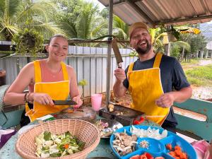 two men in aprons standing next to a table with food at Baan Panmala Guesthouse - Ao Luek in Krabi town