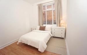 a white bedroom with a bed and a window at Stylish Retreat By Aresti Hotels in London