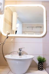 La salle de bains est pourvue d'un lavabo blanc et d'un miroir. dans l'établissement Bright Modern Apt View of the Acropolis 5 min walk, à Athènes