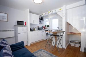 una cocina con armarios blancos y una mesa en una habitación en The Little Marlowe - 1 Bed City Centre Cottage, en Canterbury