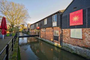 un canal en face d'un bâtiment avec un panneau sur celui-ci dans l'établissement The Little Marlowe - 1 Bed City Centre Cottage, à Canterbury