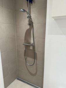 a shower with a hose in a shower stall at Attraktiv lejlighed in Odense