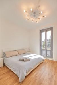 ミラノにあるLovely Apartmentの白いベッドルーム(大型ベッド1台、シャンデリア付)