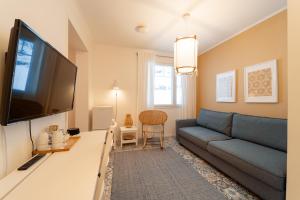 een woonkamer met een blauwe bank en een flatscreen-tv bij Hotelli Kotola in Kotka