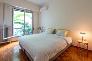 Un dormitorio con una gran cama blanca y una ventana en Tranquility Downtown Athens, en Atenas