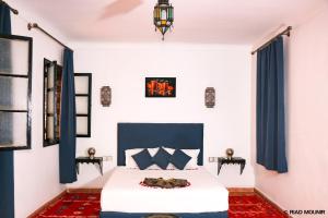 sypialnia z białym łóżkiem i niebieskimi zasłonami w obiekcie Riad Mounir w Marakeszu