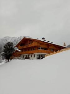 a large wooden house on top of a snow covered slope at Topp Rossmoos in Alpbach
