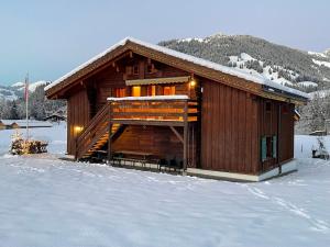 Cabaña de madera con nieve en el suelo en Alpenchalet Weidhaus Gstaad, en Gstaad