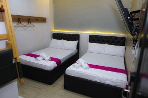 OYO 1030 Ai Hotel في مانيلا: سريرين في غرفة صغيرة مع سريرين