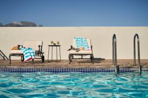two chairs sitting next to a swimming pool at The Den Apartments by Raw Africa Collection in Stellenbosch