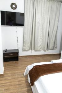 a room with a bed and a window with a television at Hotel Maranta in Pereira