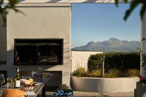 eine Terrasse mit einem Kamin und einem Tisch mit Speisen in der Unterkunft The Den Apartments by Raw Africa Collection in Stellenbosch