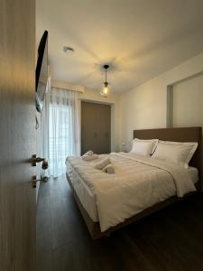 1 dormitorio con 1 cama grande con sábanas blancas en ICON Urban Living Trikala, en Tríkala