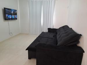 um sofá preto numa sala de estar com uma televisão em Casa de praia em Mucuri Bahia em Mucuri