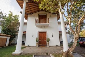 a white house with a wooden door and a balcony at Villa White Queen Resort & Spa in Galle