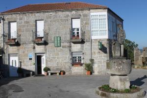 ein Steingebäude mit einer Statue davor in der Unterkunft Casa O Torgal in Parada de Sil