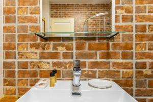 a bathroom with a sink and a brick wall at Posh Prints Studio in Budapest