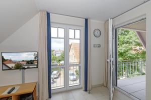 a room with a balcony with windows and a clock at Strandvilla Luv Lee Kapitaen-Suite in Rerik