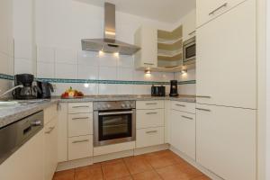 a white kitchen with white cabinets and appliances at Villa Antonia Whg_ 7 in Rerik