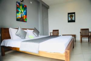 a bedroom with a large white bed with two chairs at kandy hill vilaa in Kandy