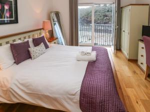 Un dormitorio con una cama grande con una ventana grande. en Curlew, en Milford Haven
