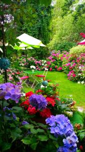 um jardim com flores rosas e roxas e um guarda-chuva em Schifferkrug Hotel & Weinstube em Celle