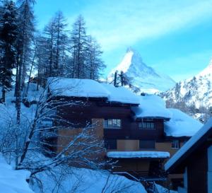 a snow covered building with a mountain in the background at Charmant studio situé au centre in Zermatt