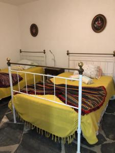 a bedroom with two beds with yellow sheets at Quintinha dos Pombinhos in Montoito