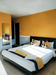 a bedroom with a large white bed with orange walls at 29 Beach House Goa in Morjim