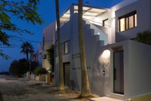 a white house with two palm trees on a street at Antigoni's Seaside Lodge, a beach retreat! in Rethymno