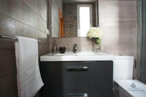 a bathroom with a sink and a toilet and a mirror at Living4malaga Guevara Apartment in Málaga
