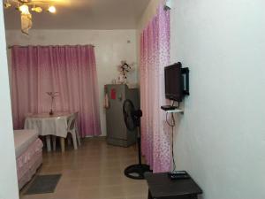 Zimmer mit rosa Vorhängen, einem TV und einem Tisch in der Unterkunft Michelle's Apartment alcoy in Alcoy