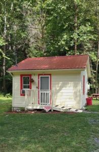 una pequeña casa con un techo rojo en el césped en Quaint Cabin By The Creek Private, en Pipestem